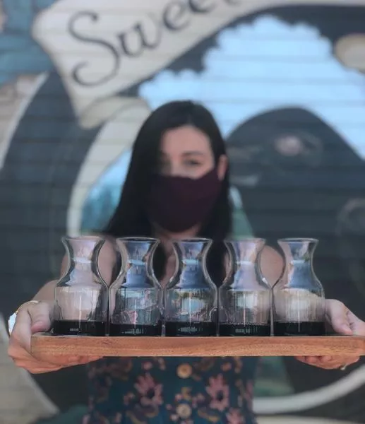 A woman holds out a flight of wine tastings