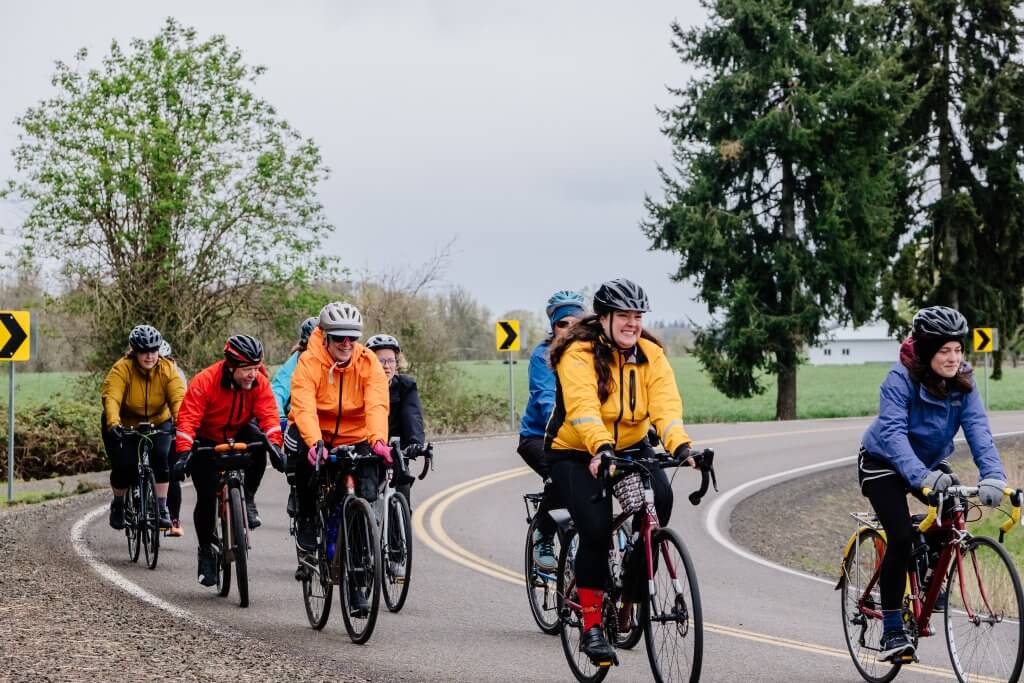 A group of people enjoying a bike ride on a country road with farms in the background. 