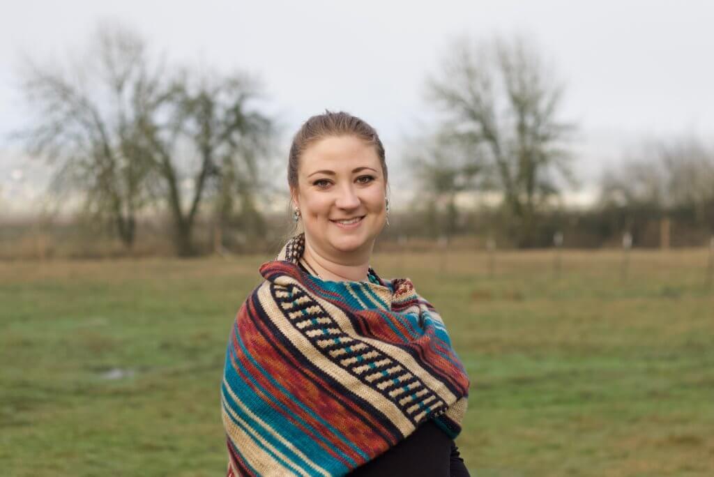 Portrait of Audrey Comerford standing in a field of grass with trees in the background.